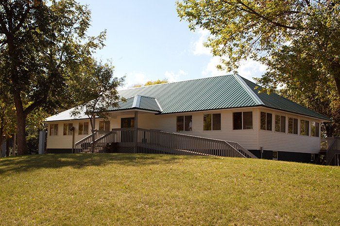 a white house with a green roof is surrounded by trees