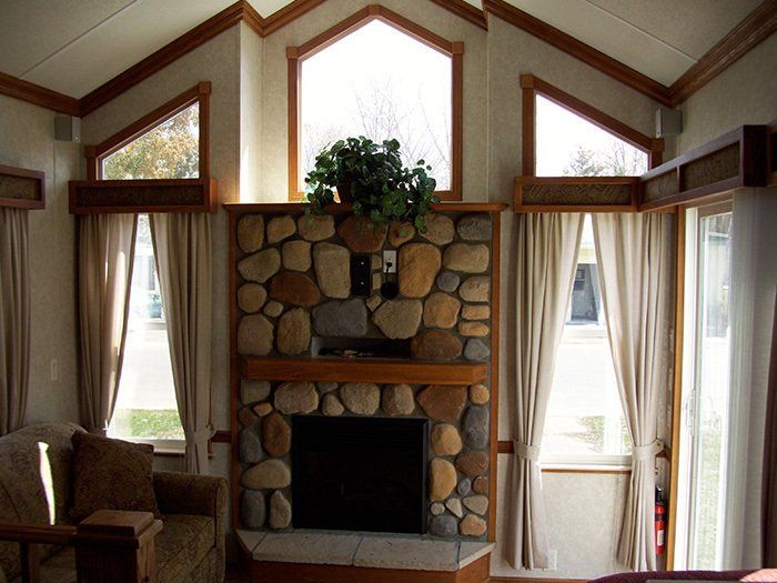 a living room with a stone fireplace and lots of windows