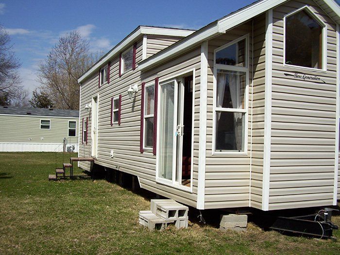 a tiny house with a sliding glass door is parked in a grassy field .