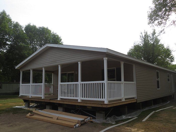 a mobile home with a large porch and white railing