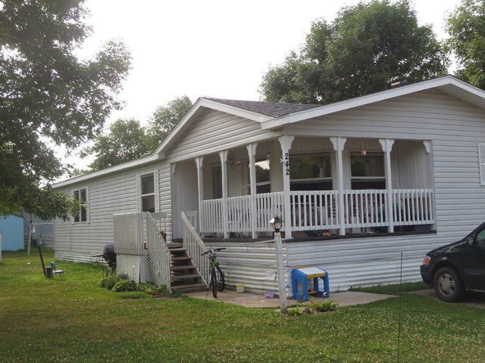 a white mobile home with a porch and stairs
