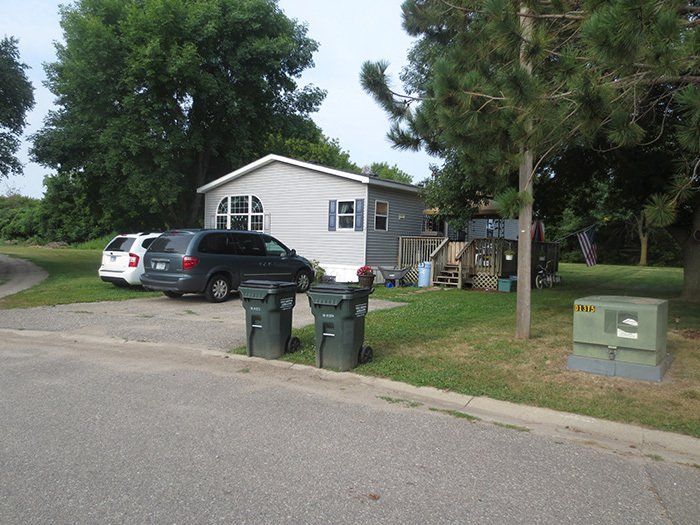a mobile home with two trash cans in front of it