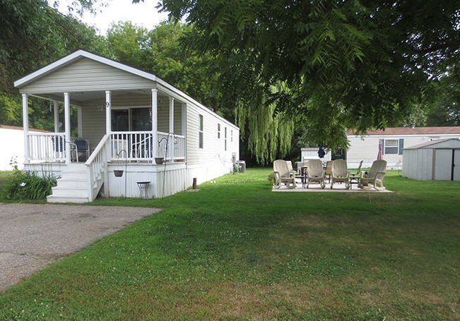 a mobile home with a porch and chairs in front of it .