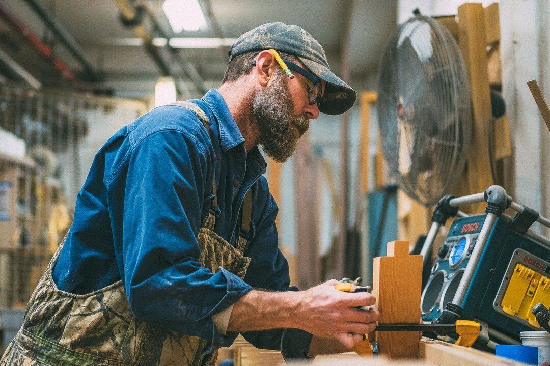 A man is working on a piece of wood in a workshop.