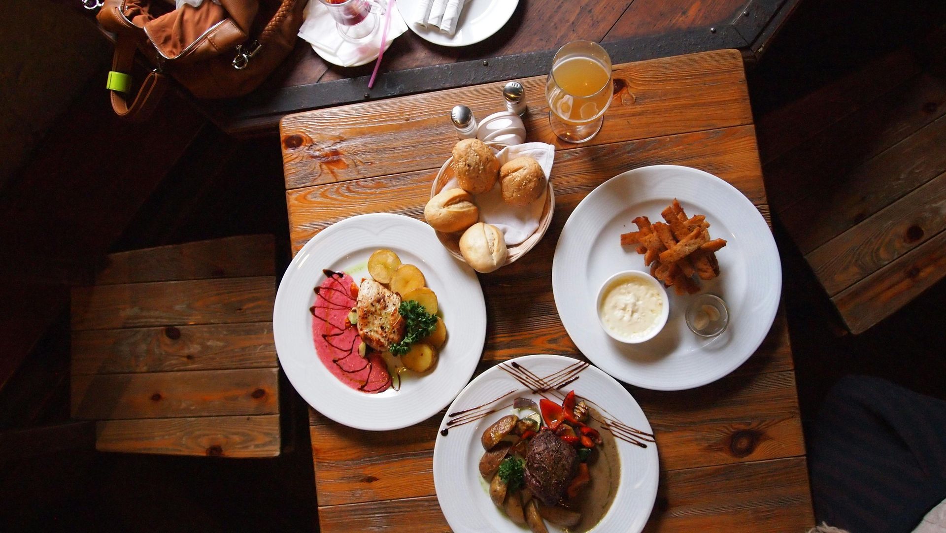 Three plates of food are on a wooden table.