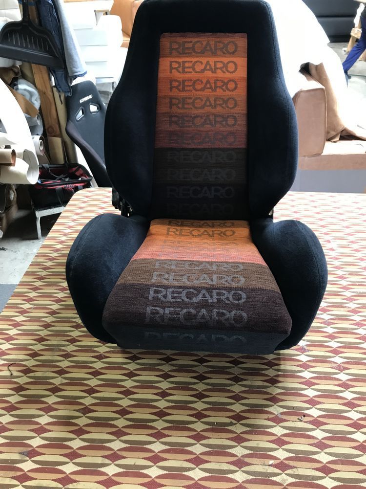 Black Recaro car seat with orange and brown striped center, Recaro logo printed.