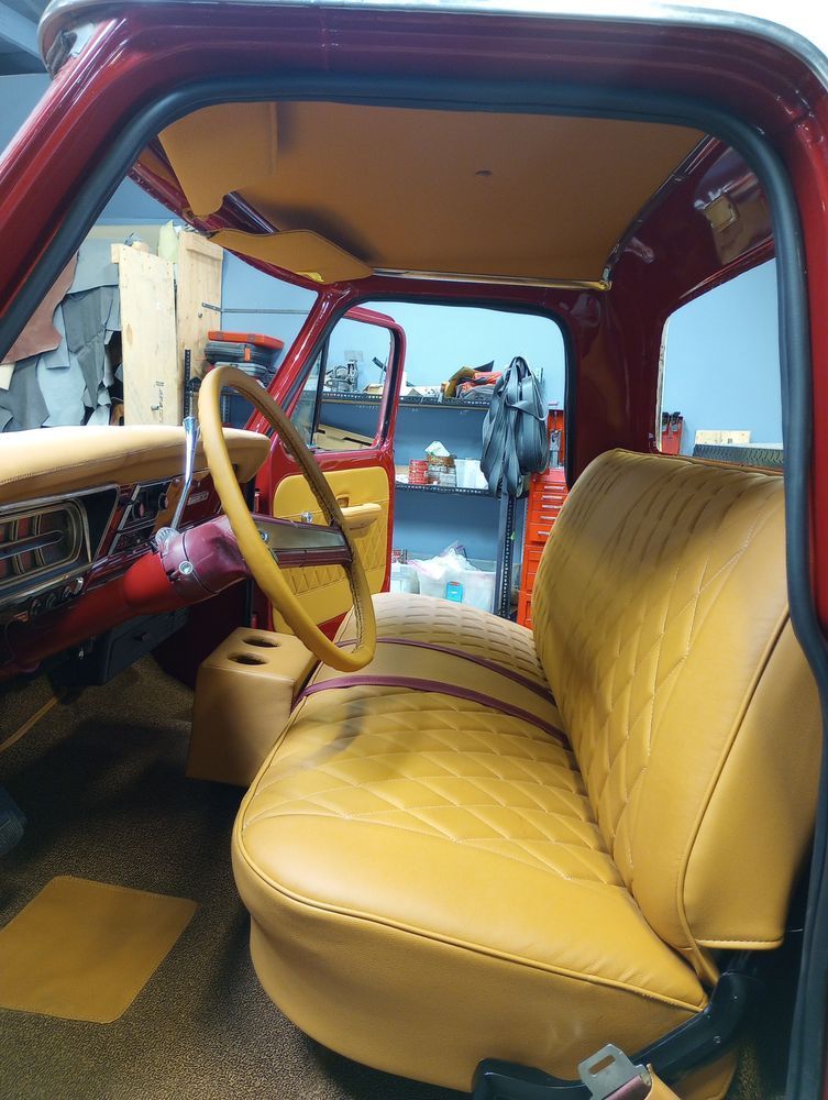 Red classic truck interior with tan leather seats, steering wheel, and headliner.