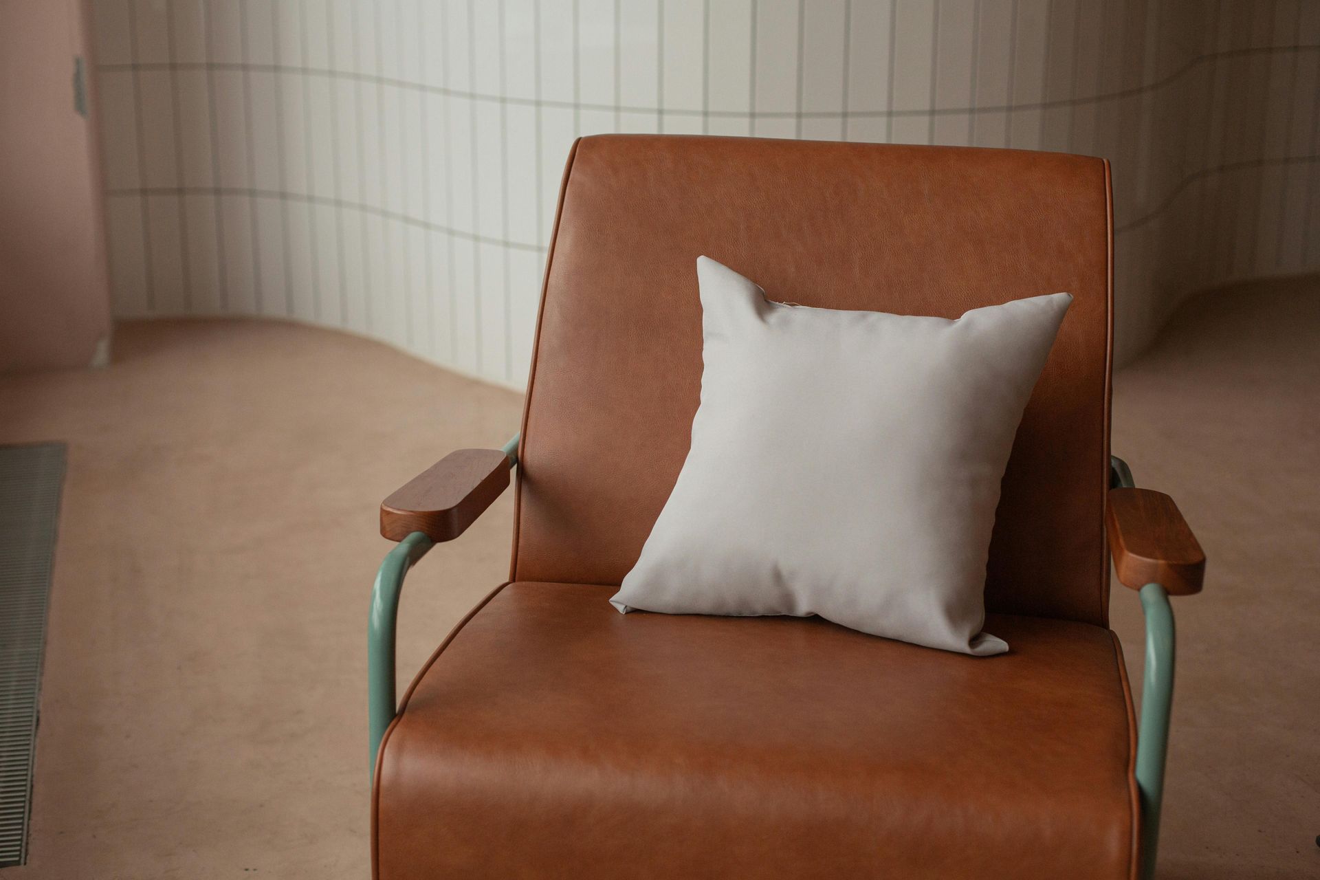 Brown leather armchair with a light gray pillow.