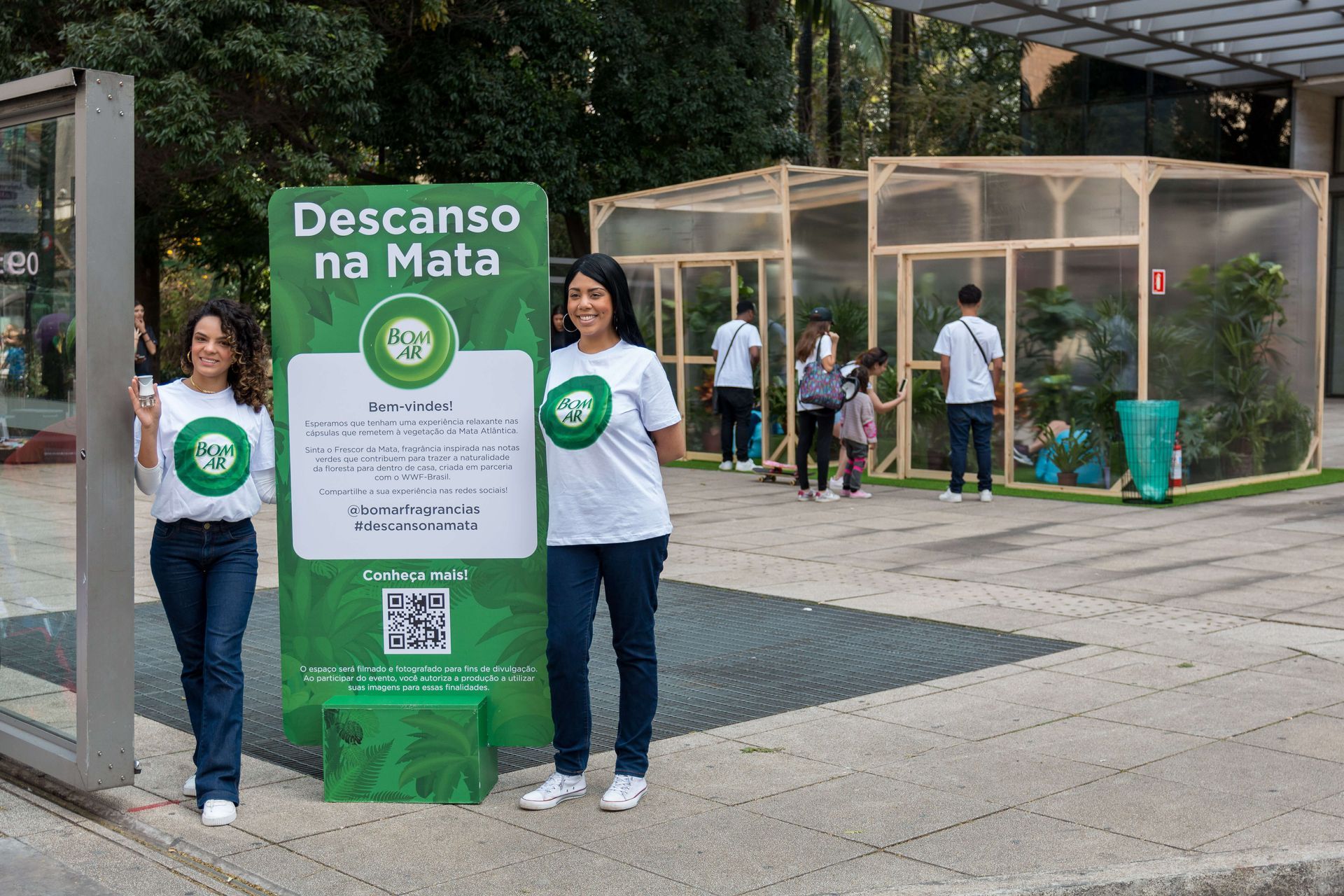 imagem da promoção do produto Bom Ar Frescor da mata. Duas mulheres ao lado de um totem promocional com atenda ao fundo