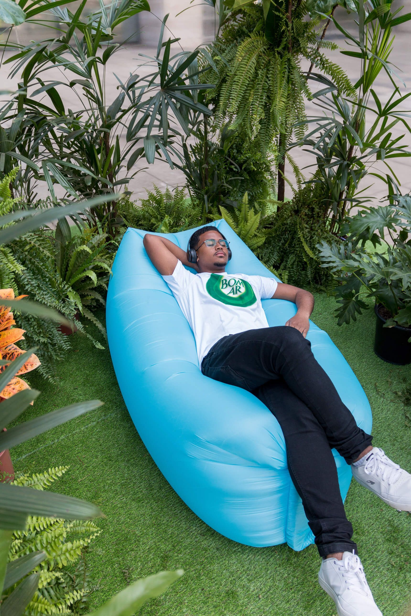 imagem da promoção do produto Bom Ar Frescor da mata. Homem deitado em um puff dentro da tenda promocional