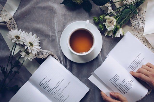2 libros abiertos cerca de una taza de café y flores