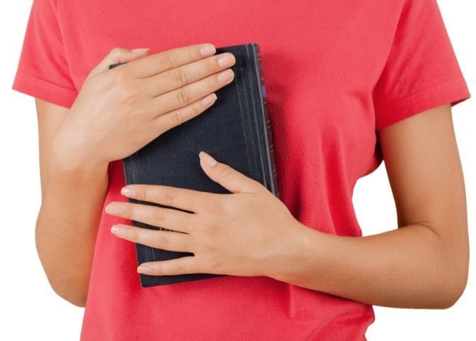 Imagen del torso de una mujer abrazando un libro de creencias