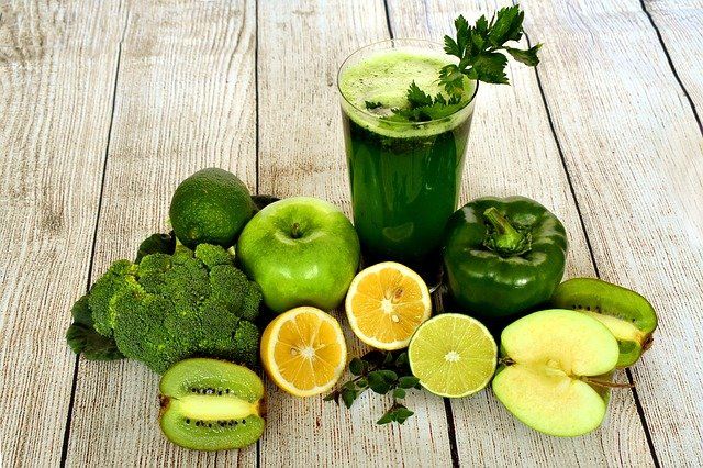 Jugo verde con frutas y verduras alrededor