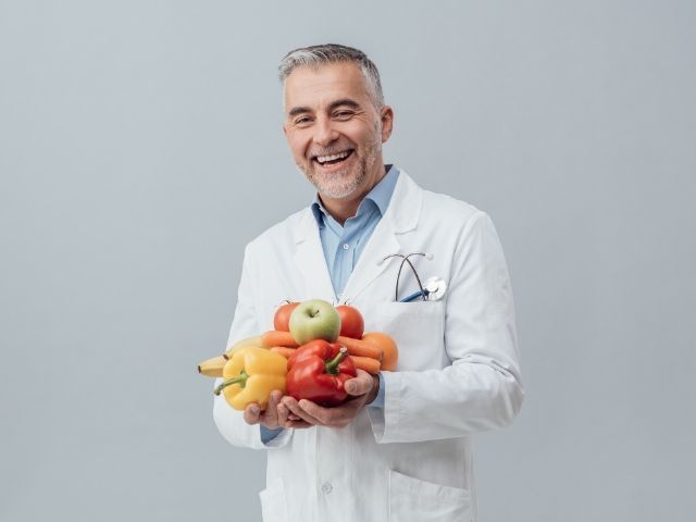 Médico feliz con vegetales en las manos