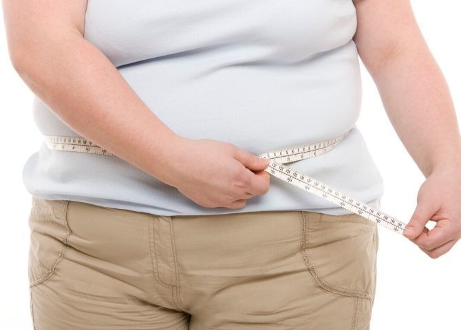 Torso de mujer obesa midiéndose para ilustrar que la obesidad y el sobre peso son una pandemia
