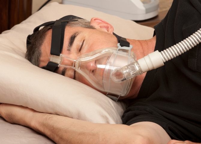 paciente durmiendo con una máquina para la apnea del sueño, que la cirugía bariátrica puede ayudar a eliminar