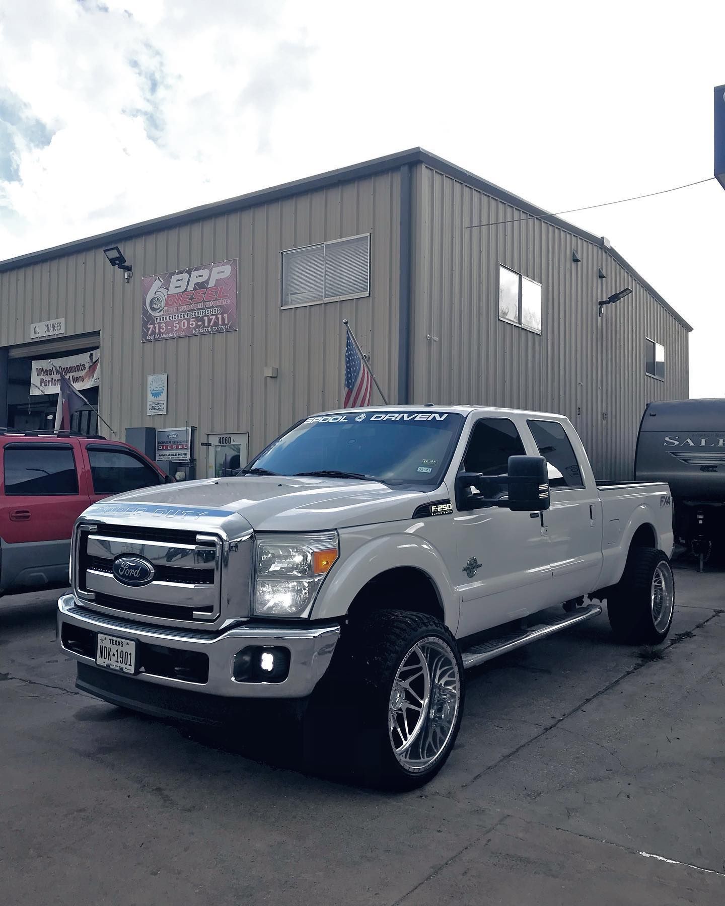 A car is being adjusted on a lift in a garage.