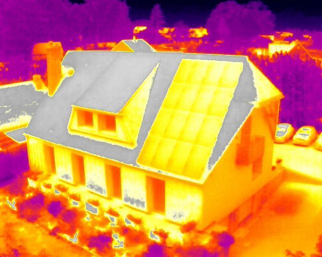 Image thermique d'une maison équipée de panneaux solaires, montrant les signatures thermiques en jaune et orange.