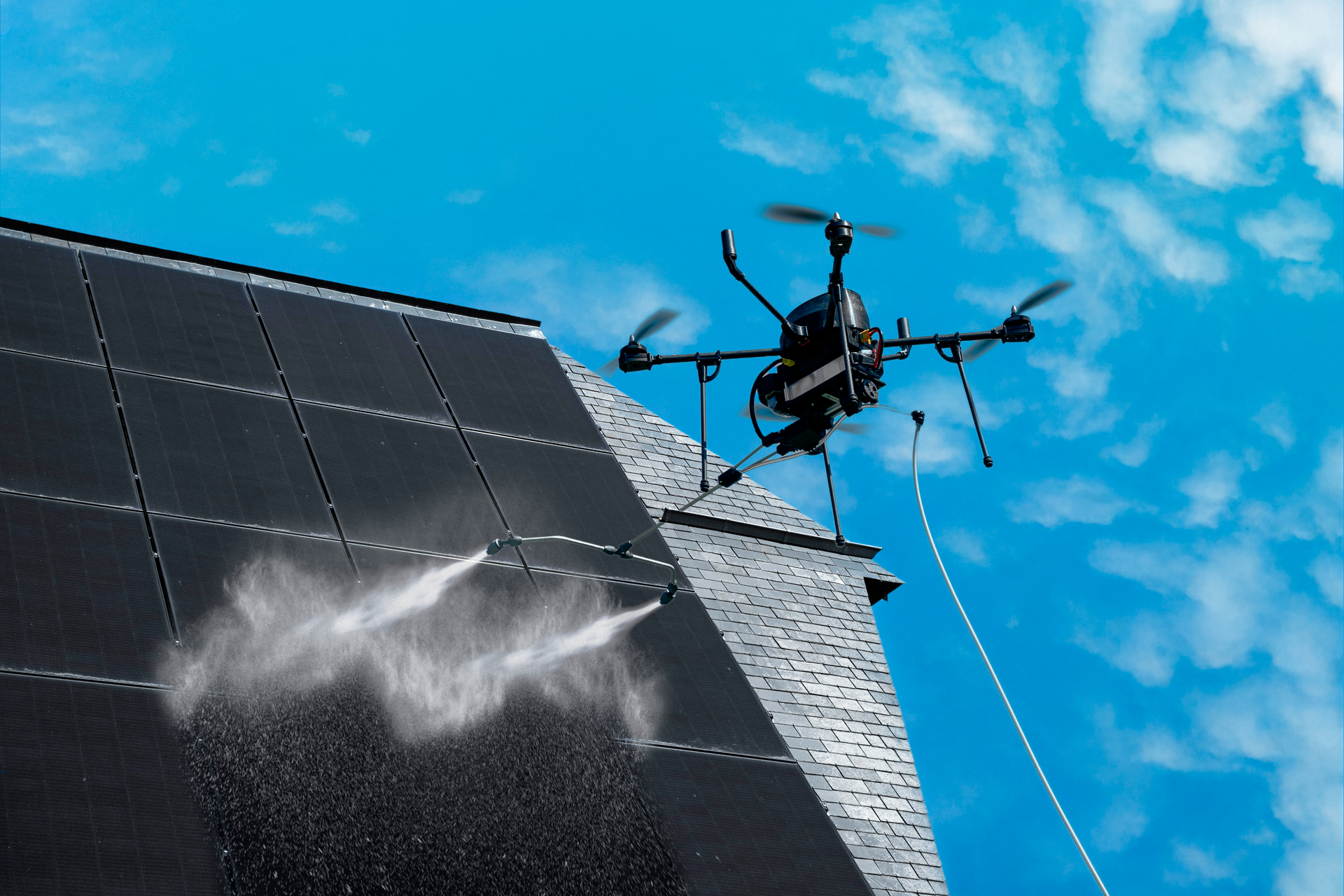 Un drone pulvérise de l'eau sur des panneaux solaires, le tout sur fond de ciel bleu.