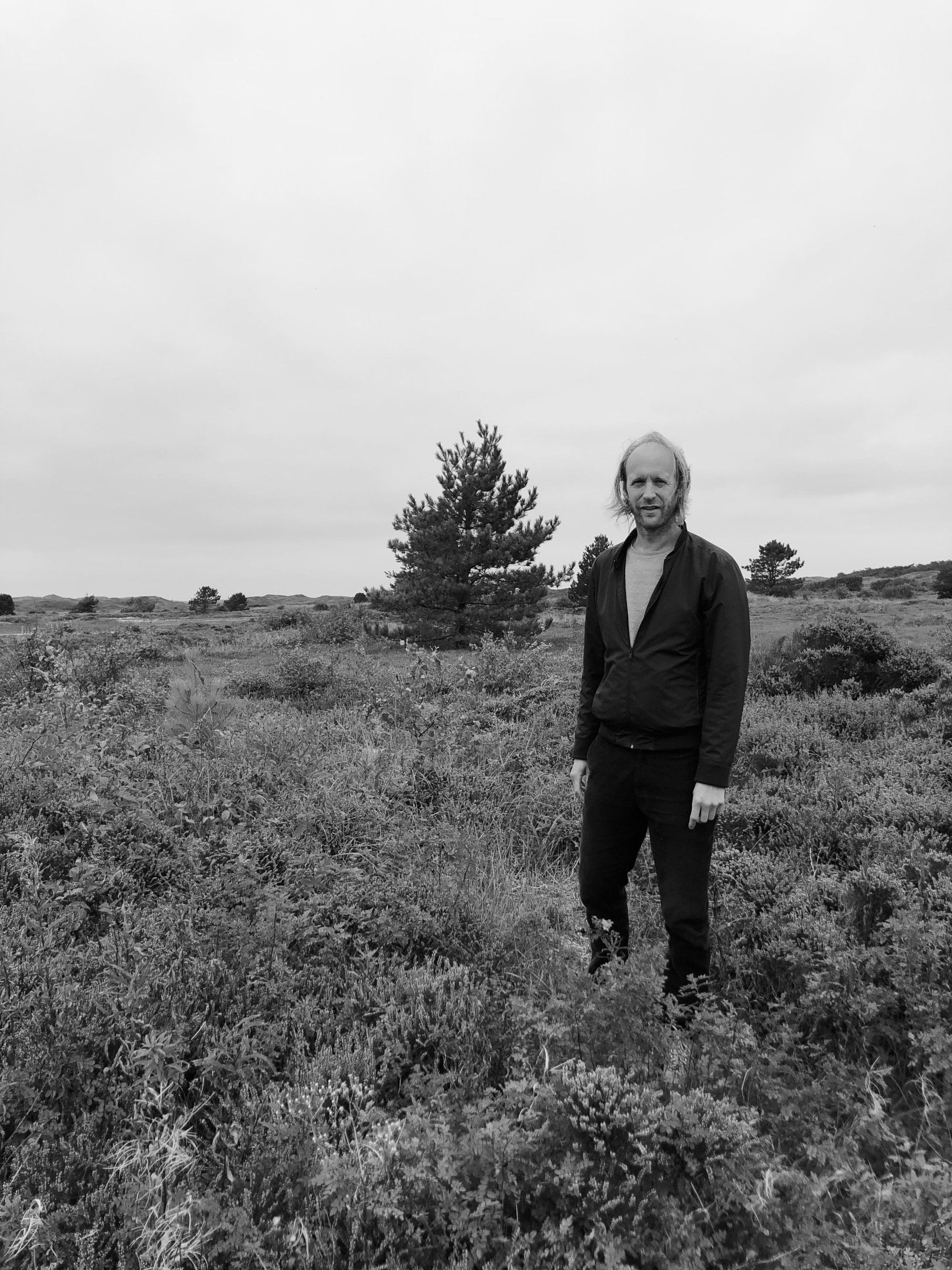 Black and white photo of man standing in dunes the Netherlands, Texel