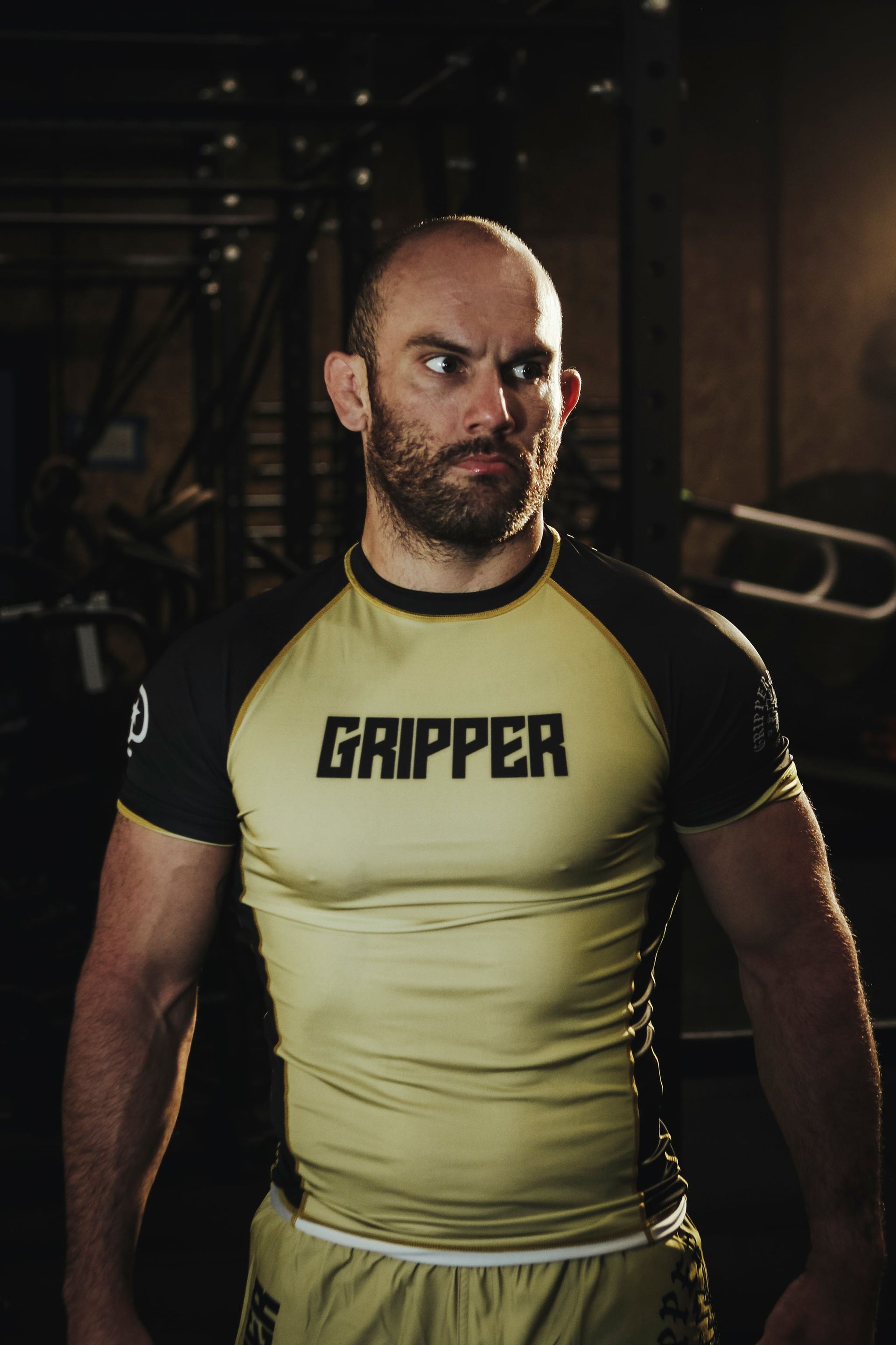a man with a beard is wearing a gripper shirt and shorts .