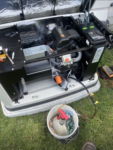 Generator with open housing, tools, and bucket on grass.