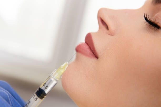 Woman receiving chin injection with a syringe; close-up.