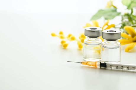 Syringe and vial of clear liquid on a white background, likely medical equipment.