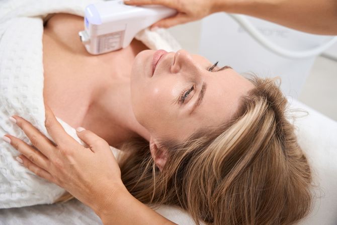 Woman receiving neck and face treatment at a spa.