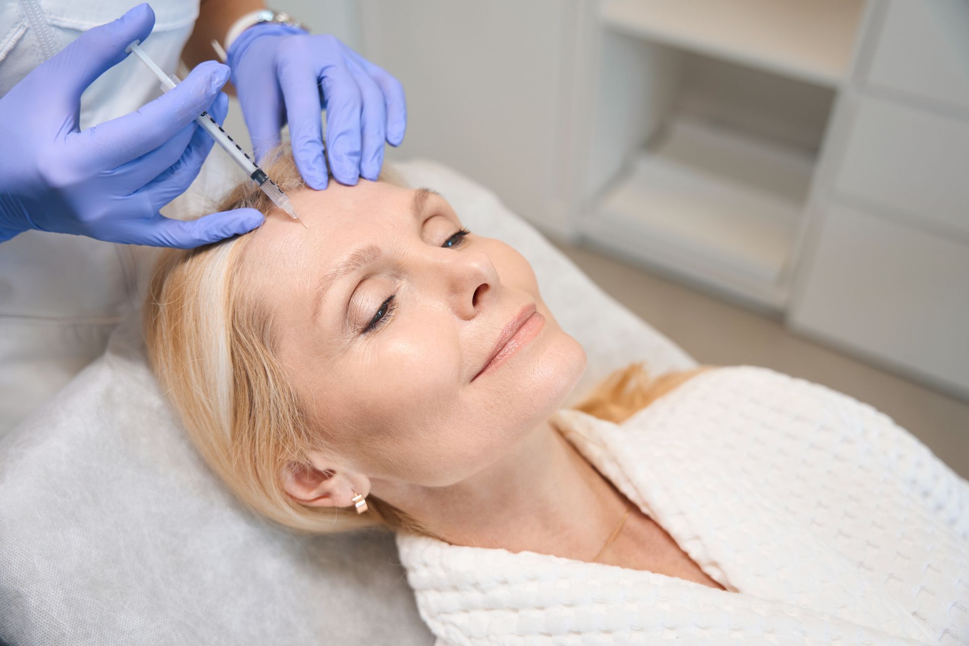 Person receiving a cosmetic injection in a medical setting.