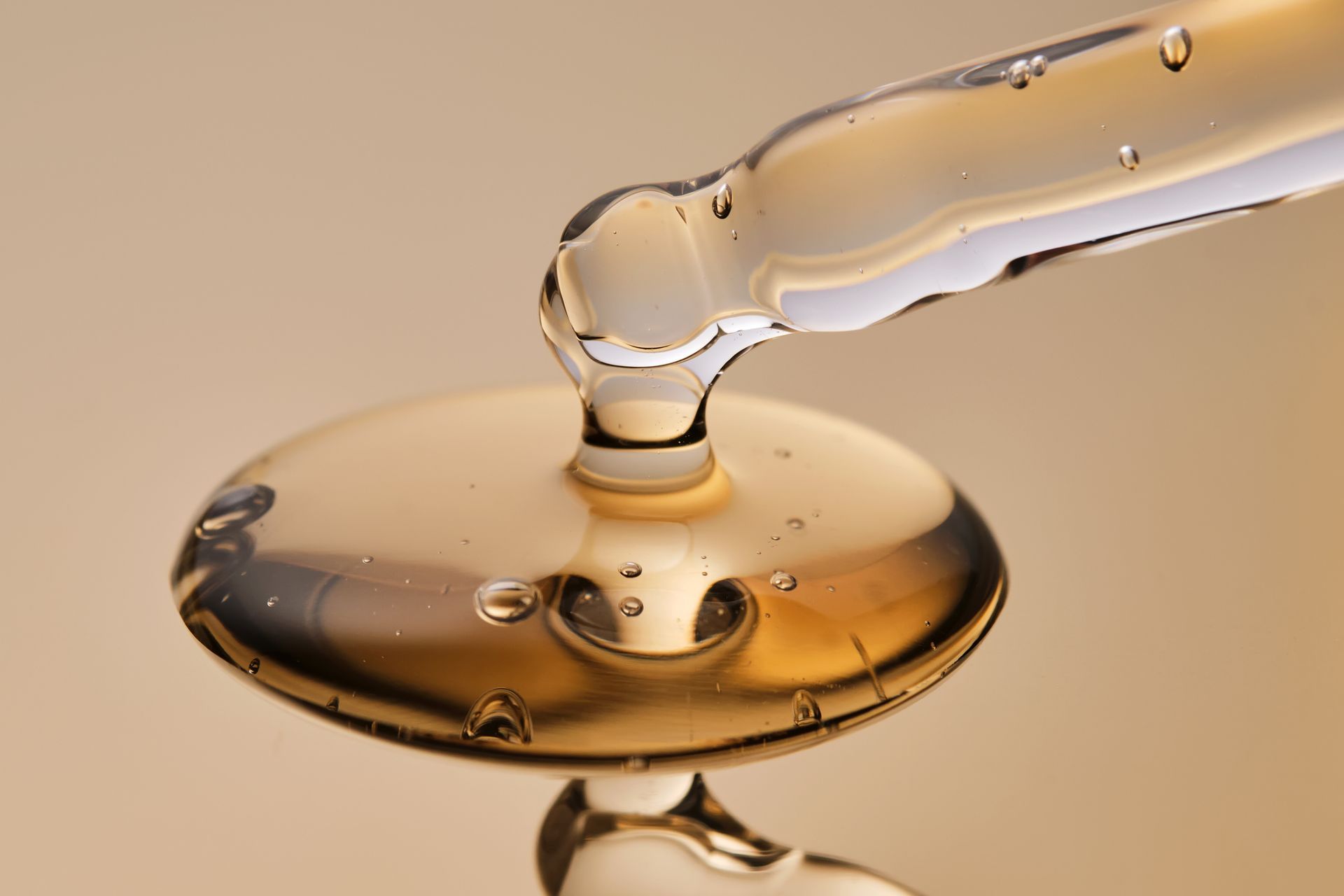 Dropper dispensing golden liquid onto a reflective surface, close-up shot. Dropper dispensing golden liquid onto a reflective surface, close-up shot.
