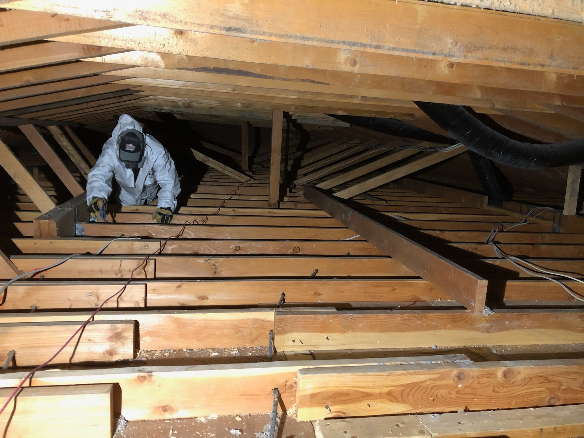 A man is standing in the attic of a house.