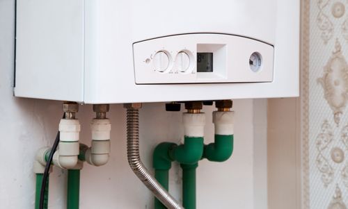 A white water heater with green pipes attached to it.