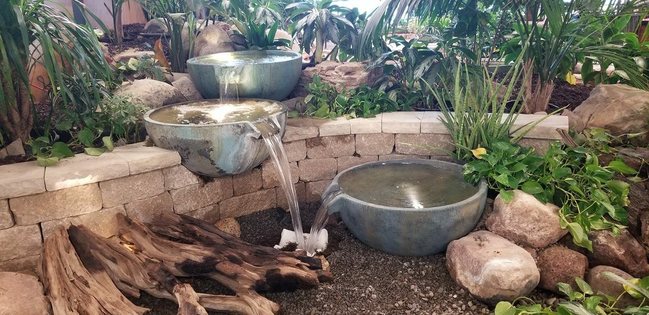 A water fountain is surrounded by rocks and plants in a garden.