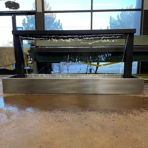 A water fountain is sitting on a table in front of a window