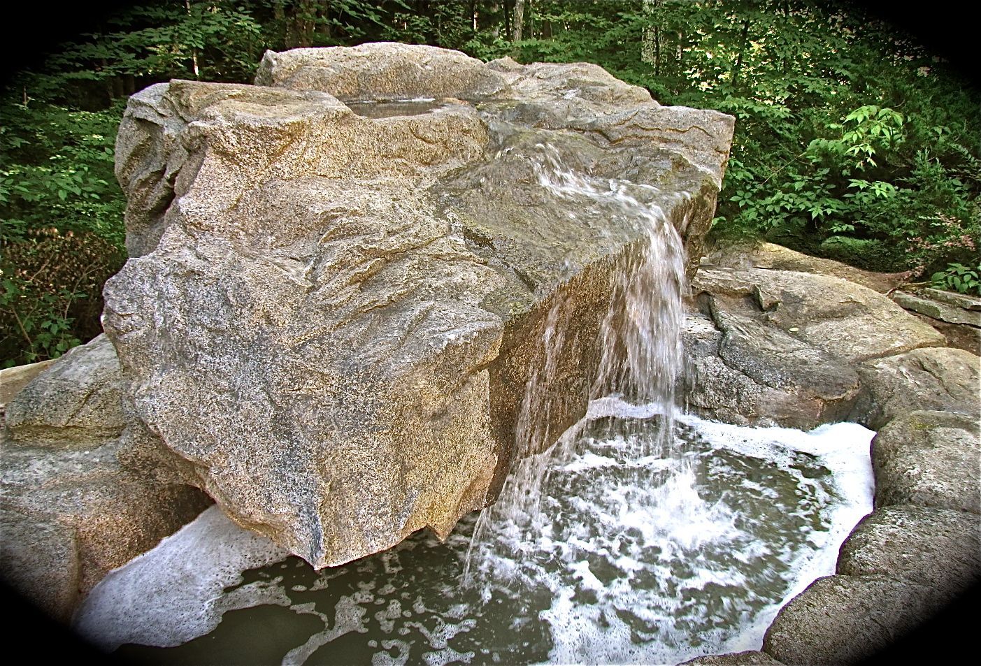 A waterfall is surrounded by rocks in the middle of a forest.