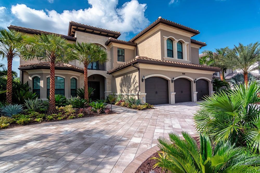 A large house with a driveway and palm trees in front of it.