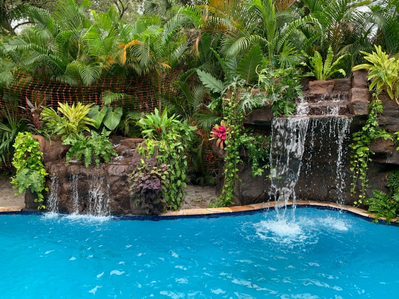 There is a waterfall in the middle of a swimming pool.