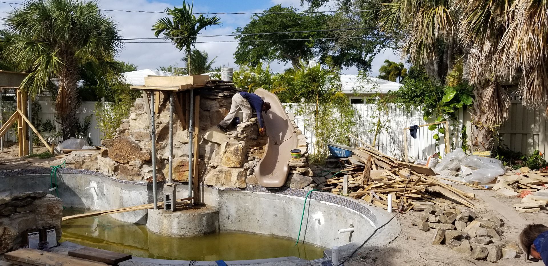 A man is working on a waterfall in the backyard of a house.