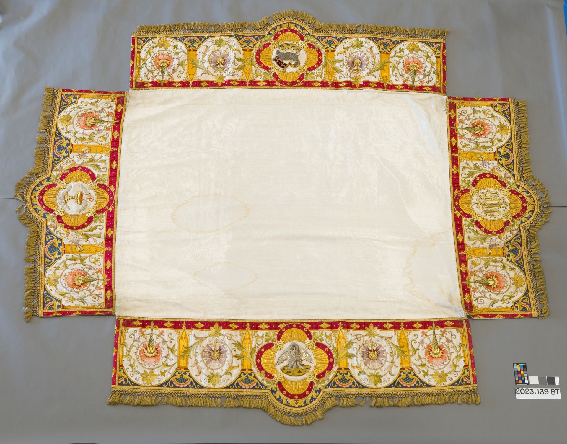 A white rectangular cloth centered within a wide, decorative border featuring intricate gold embroidery and floral motifs.