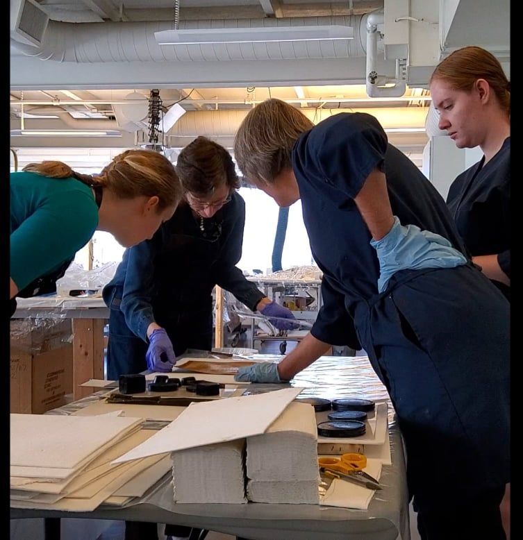 A group of people standing around a table looking at something