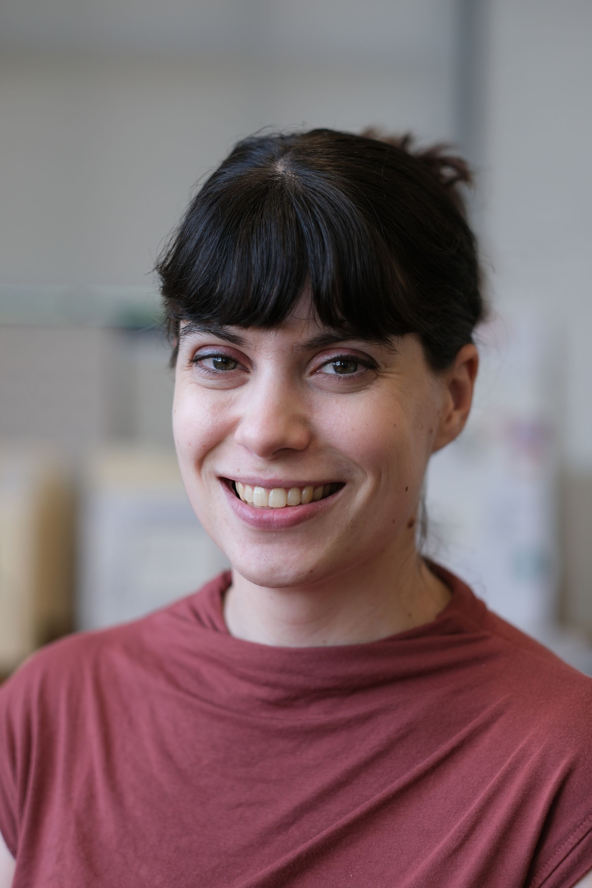 A woman in a red shirt is smiling for the camera.