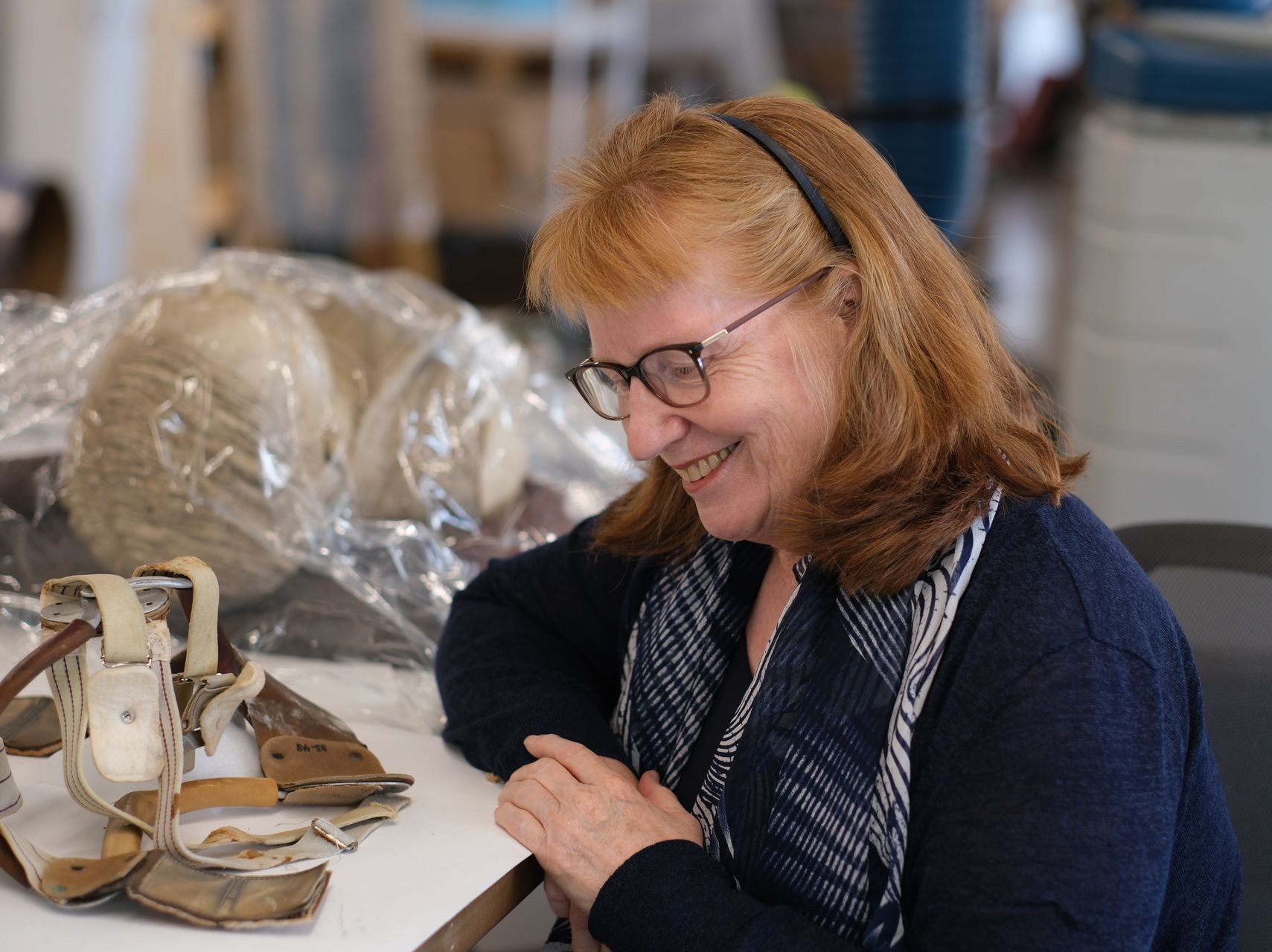 A woman wearing glasses is smiling while sitting at a table.