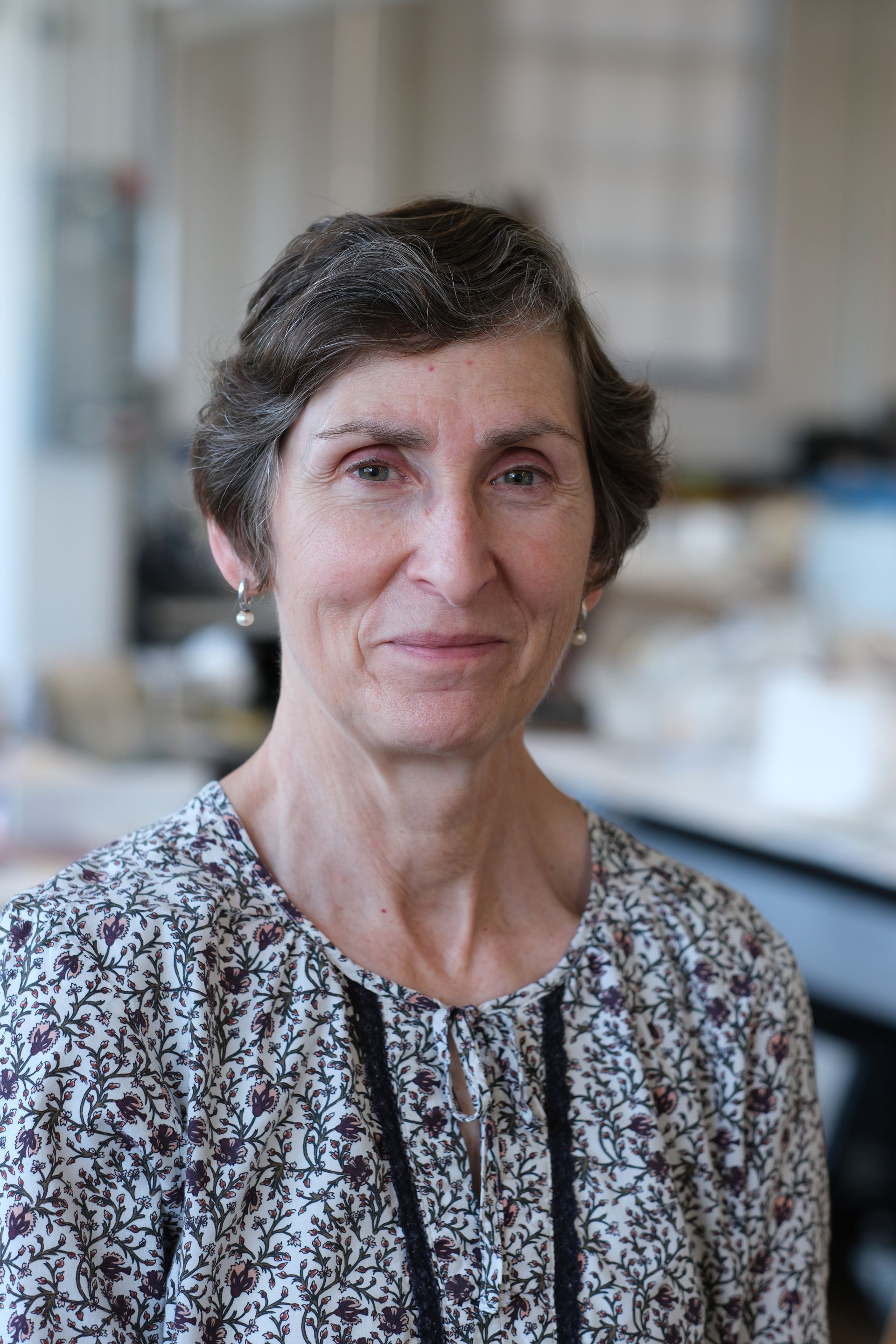 A woman in a floral shirt is smiling for the camera.