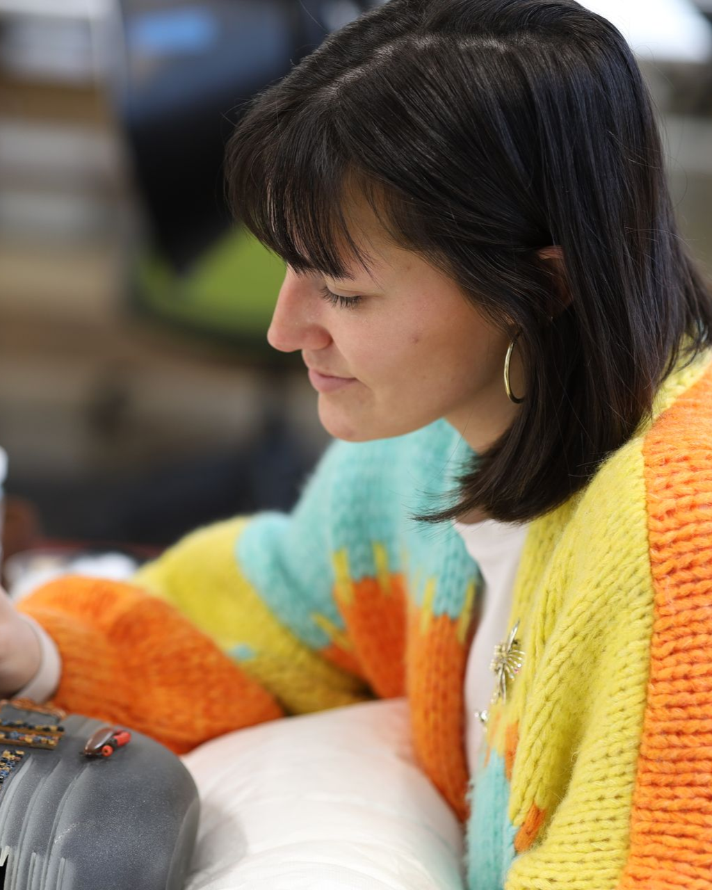 A woman in a blue shirt and glasses is sitting at a table with her arms crossed.
