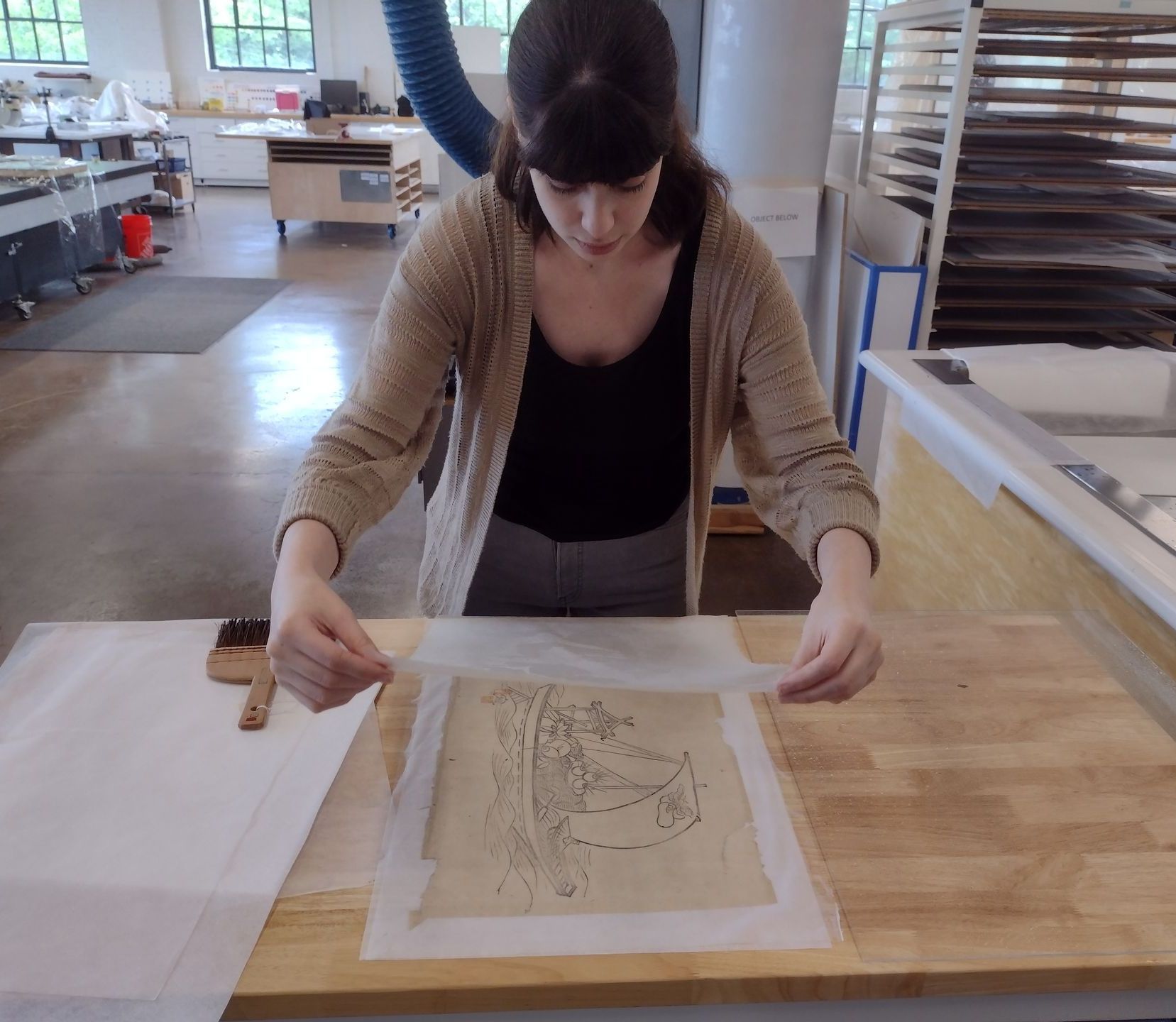 A woman is working on a piece of paper on a wooden table