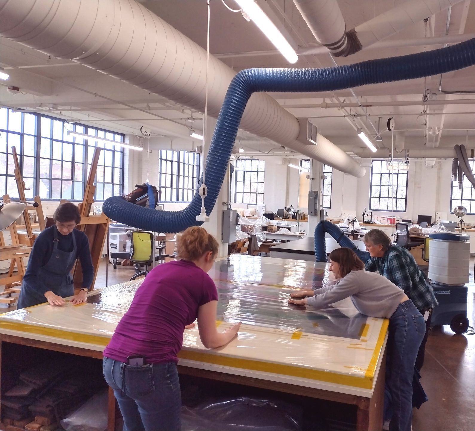 A group of people standing around a table with a blue hose hanging from the ceiling