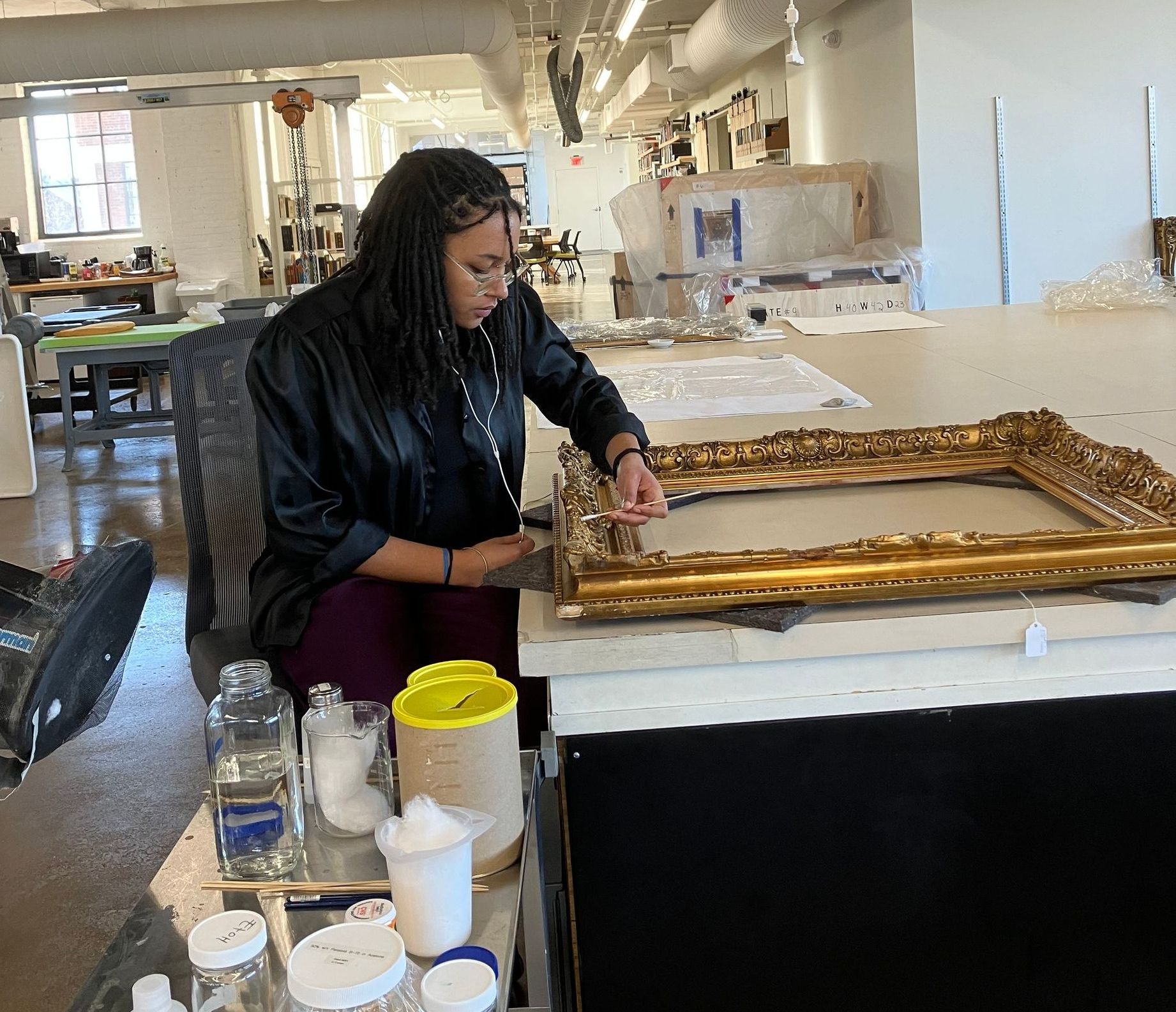 A woman is sitting at a table working on a picture frame