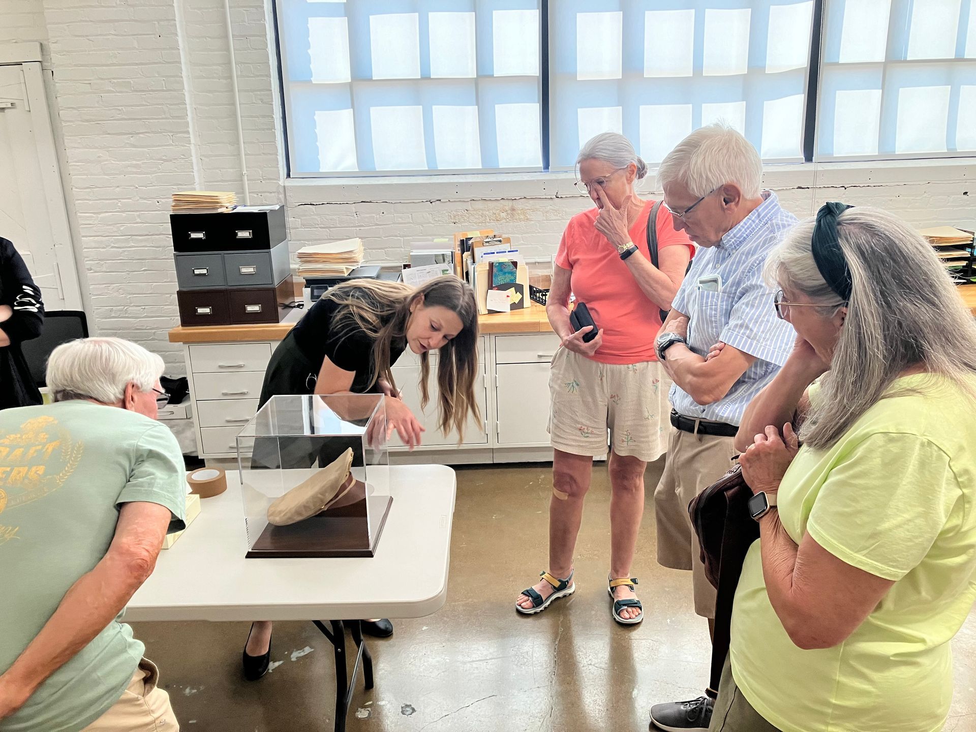 A group of people are standing around a table looking at a sculpture.