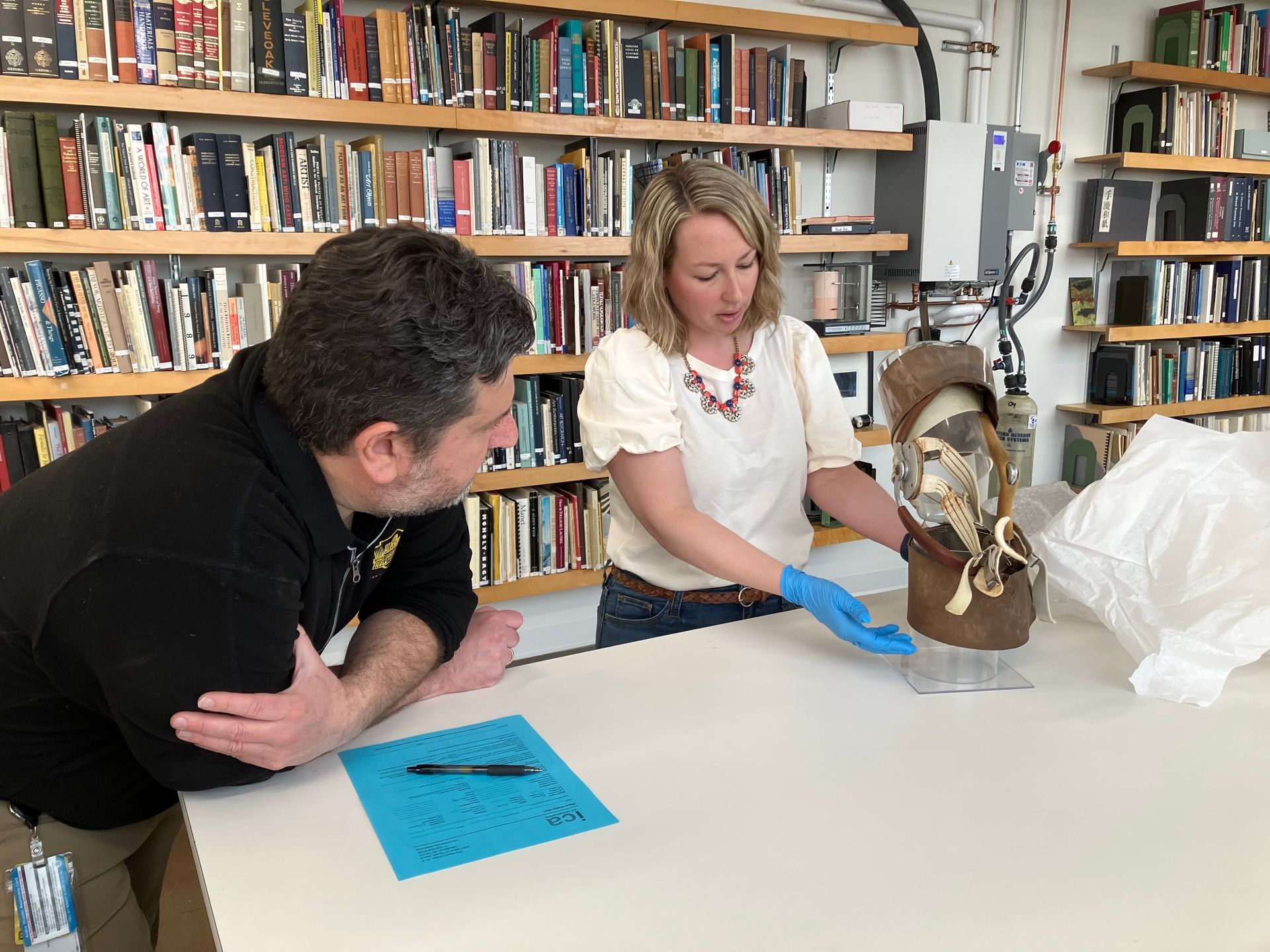 A man and a woman are looking at a statue in a library.